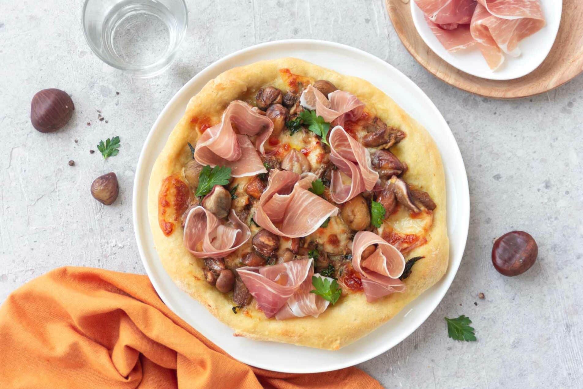 Pizza mit Esskastanien, Pilzen, San Daniele-Schinken und geräuchertem Scamorza-Käse