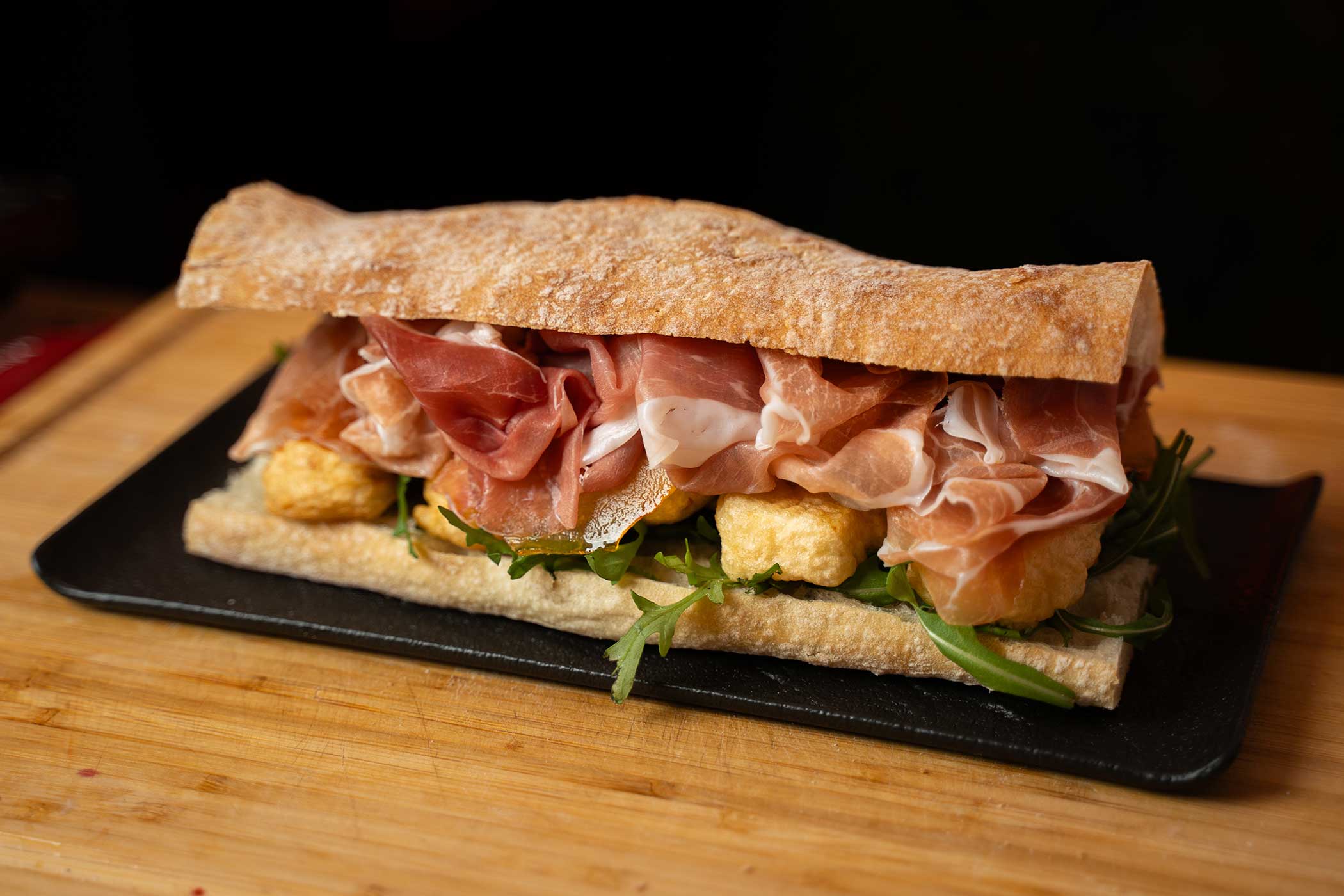 Panino con pere caramellate, brie in tempura, rucola e Prosciutto di San Daniele