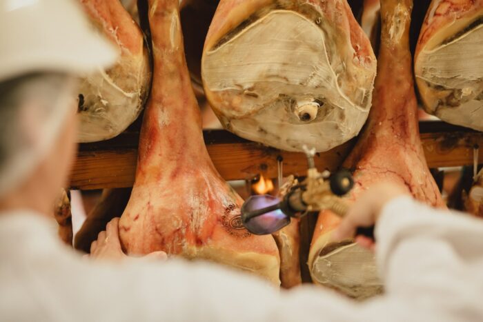 cosce di prosciutto di san daniele a cui viene applicato il marchio dop