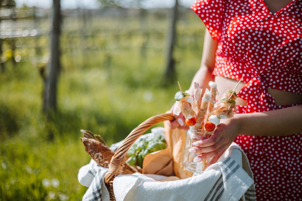 primo piano di cesto da pic nic con prodotti alimentari come pane, grissini e prosciutto di san daniele