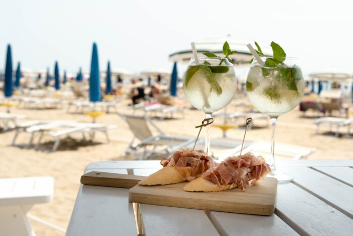 aperitivo in una località balneare: tavolo con pane, prosciutto e cocktail sulla spiaggia