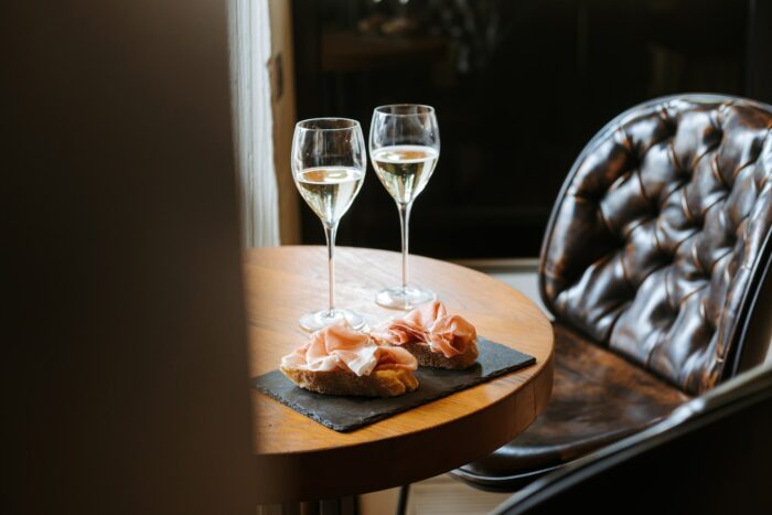 crostini di pane con prosciutto di san daniele e due calici di vino bianco su un tavolino