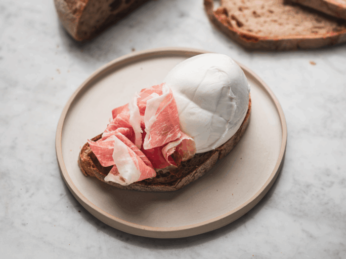 fetta di pane con una fetta di prosciutto di san daniele e una mozzarella fresca