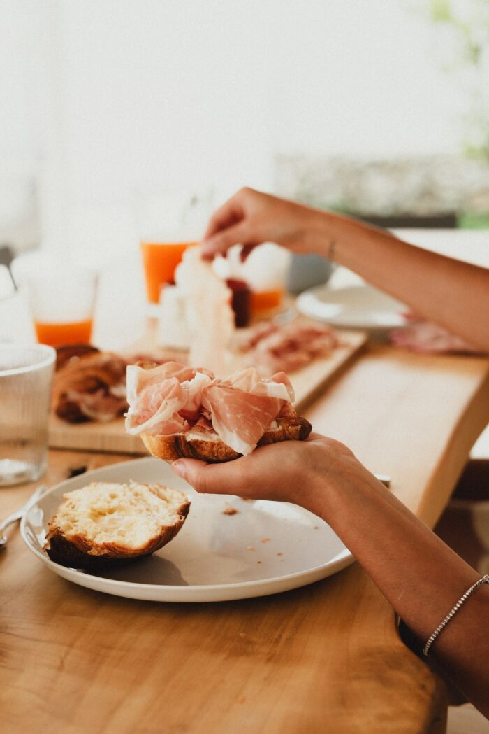 persona che prepara un crostino di pane con prosciutto di san daniele