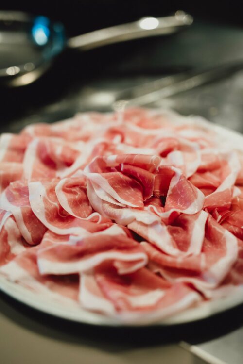 piatto bianco con fette di prosciutto di san daniele tagliate sottili