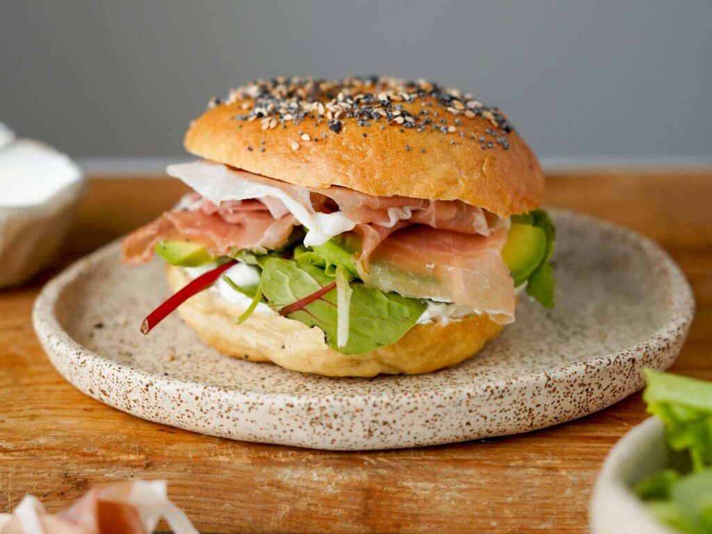 Bagel con formaggio spalmabile, avocado, insalata e San Daniele