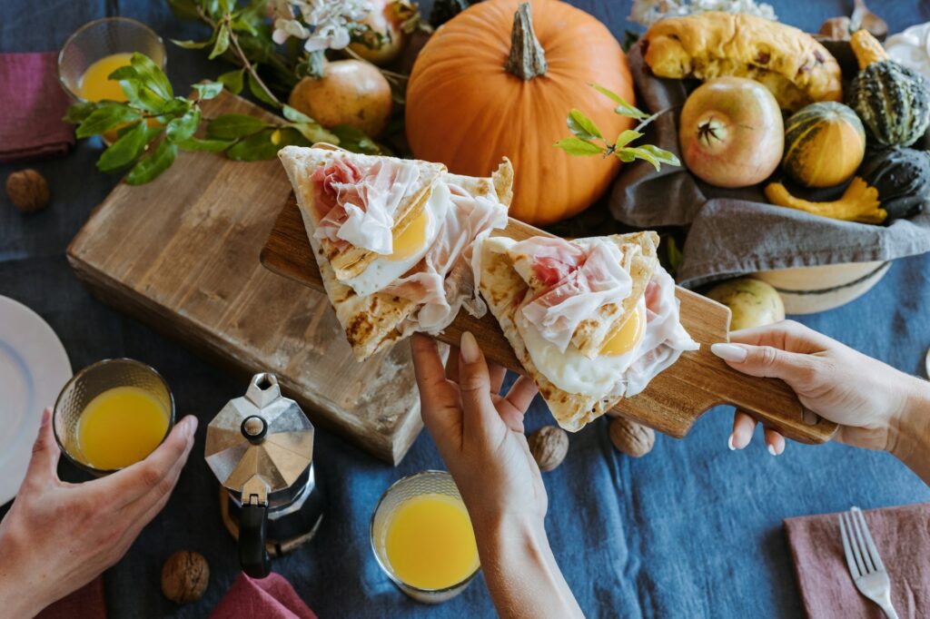 tavola imbandita con zucche, bicchieri di aranciata e tranci di focaccia con prosciutto di san daniele
