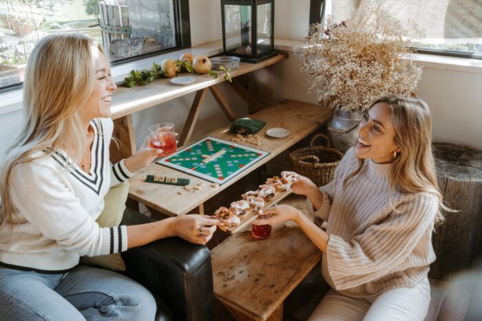 ragazze che si godono una giornata autunnale giocando a scarabeo, bevendo cocktail e mangiando tartine con prosciutto di san daniele