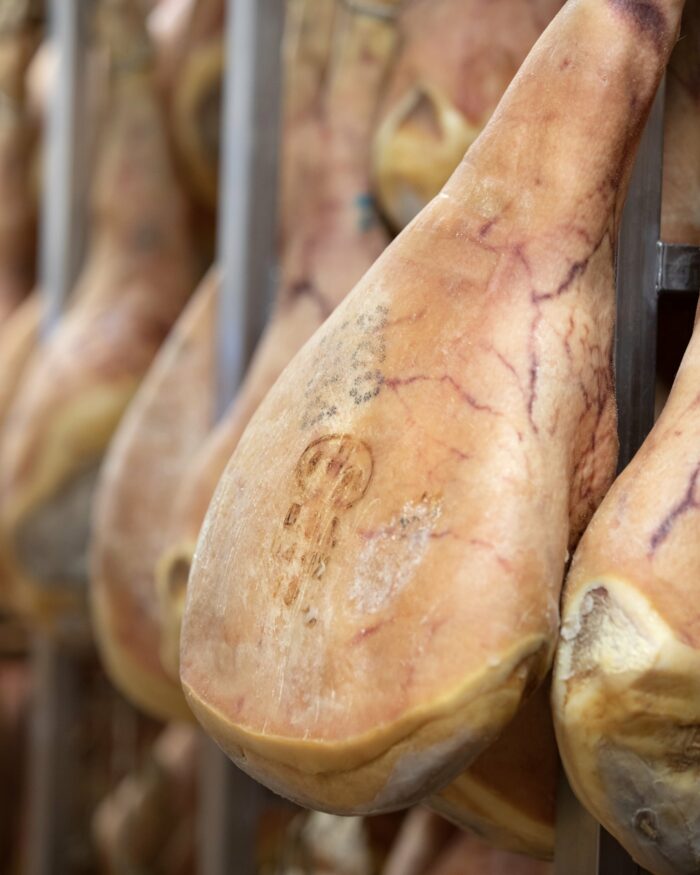 cosce di prosciutto di san daniele appese con marchio in evidenza sulla cotenna