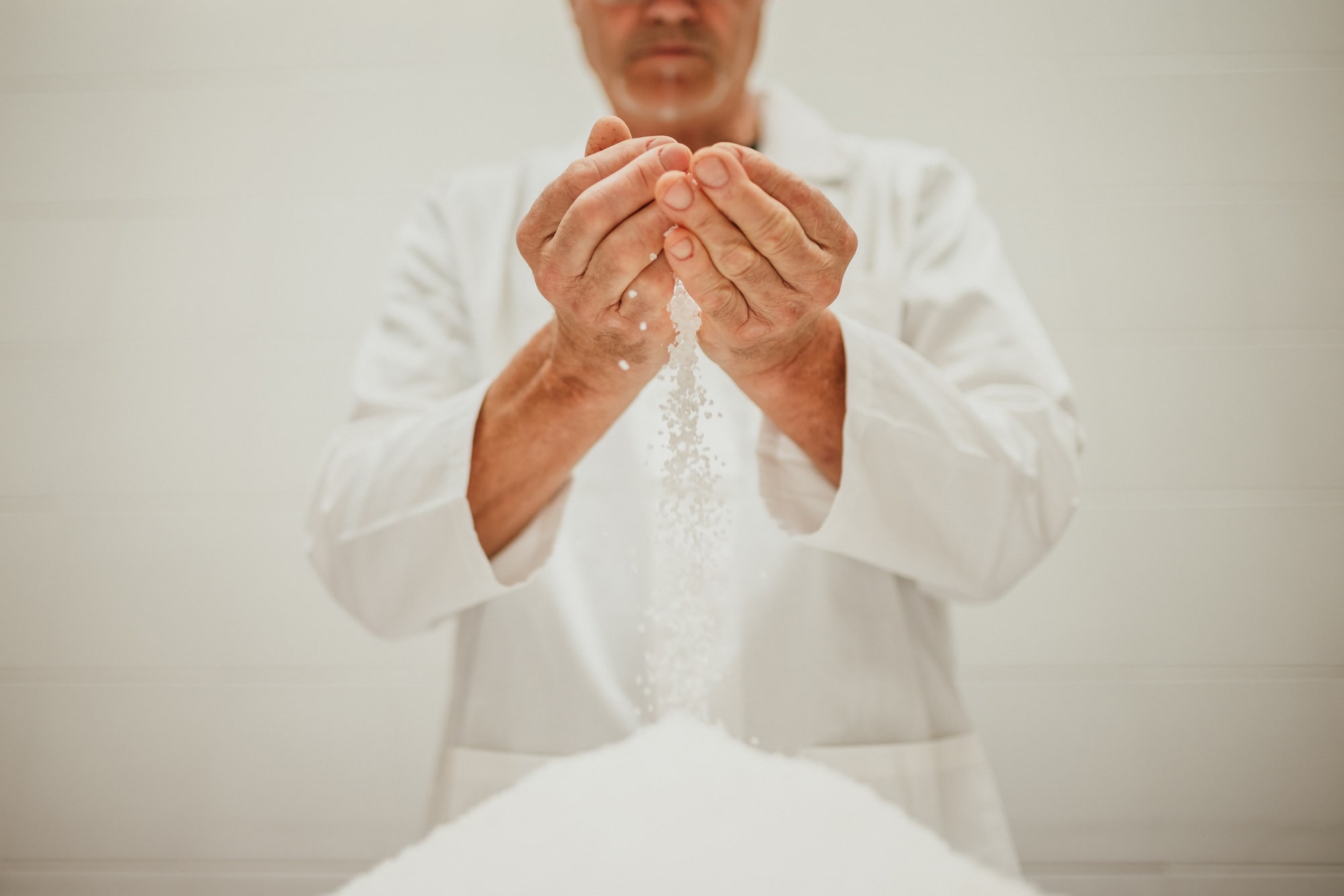 operatore che tiene tra le mani il sale, uno degli ingredienti principali del prosciutto di san daniele senza conservanti