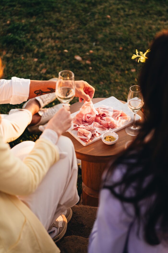 abbinamento tra vino e prosciutto di san daniele: persone che fanno aperitivo insieme con calici di vino e fette di pane con il prosciutto