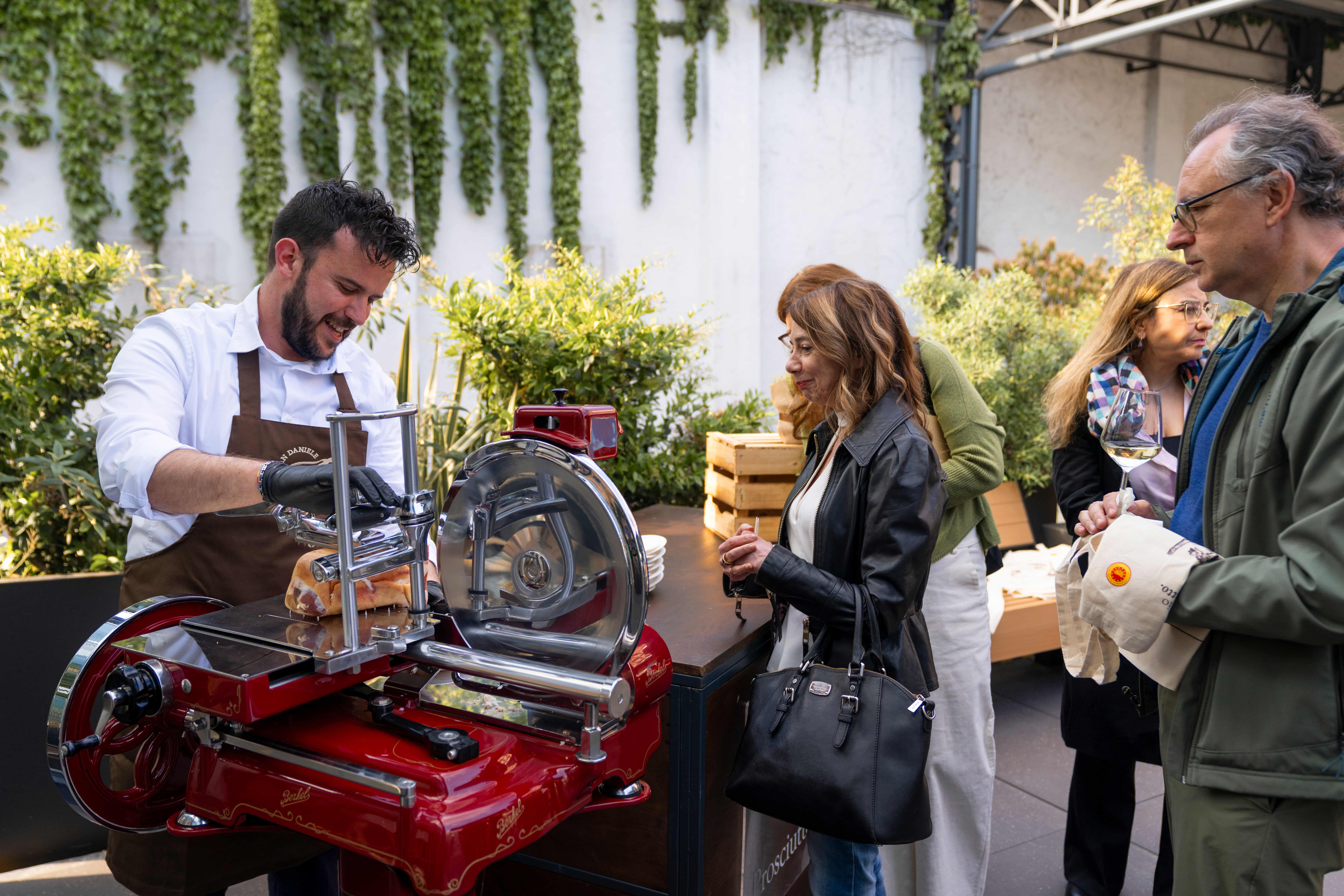 Affettatore taglia il Prosciutto di San Daniele DOP con affettatrice Berkel a volano durante la degustazione all'evento Essenza a Milano