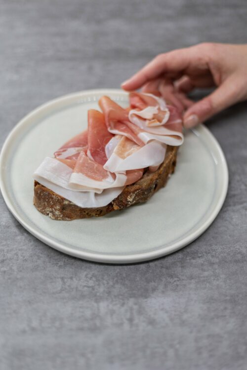 Fette di Prosciutto di San Daniele con grasso bianco visibile adagiate su pane rustico