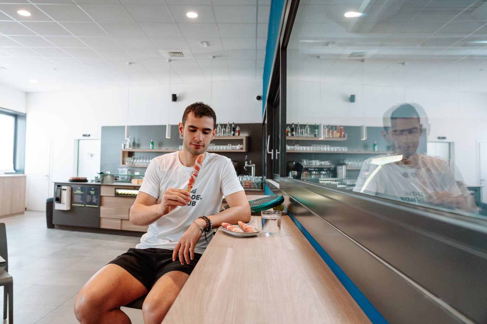 Giovane sportivo mangia Prosciutto di San Daniele come spuntino post allenamento in un padel club