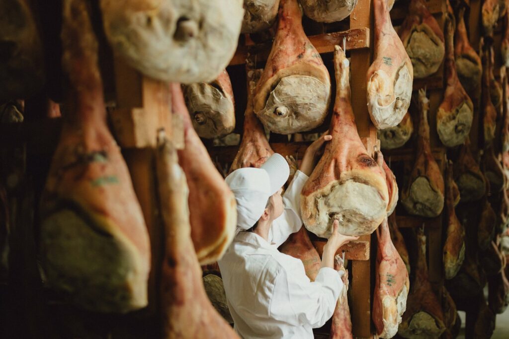 Mastra prosciuttaia controlla le cosce appese durante la stagionatura del Prosciutto di San Daniele DOP