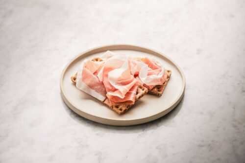 Fette di Prosciutto di San Daniele su pane integrale croccante, esempio di consumo equilibrato