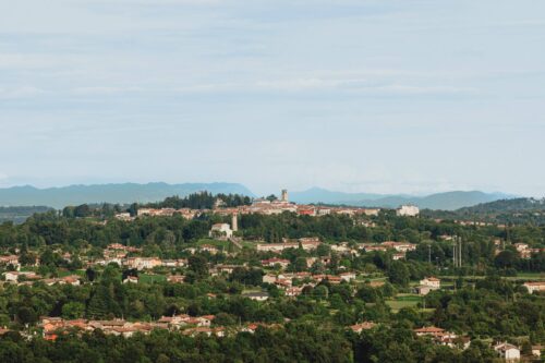 Vista panoramica di cosa visitare a San Daniele del Friuli: il borgo sul Colle Massimo con il campanile del Duomo e le Prealpi sullo sfondo