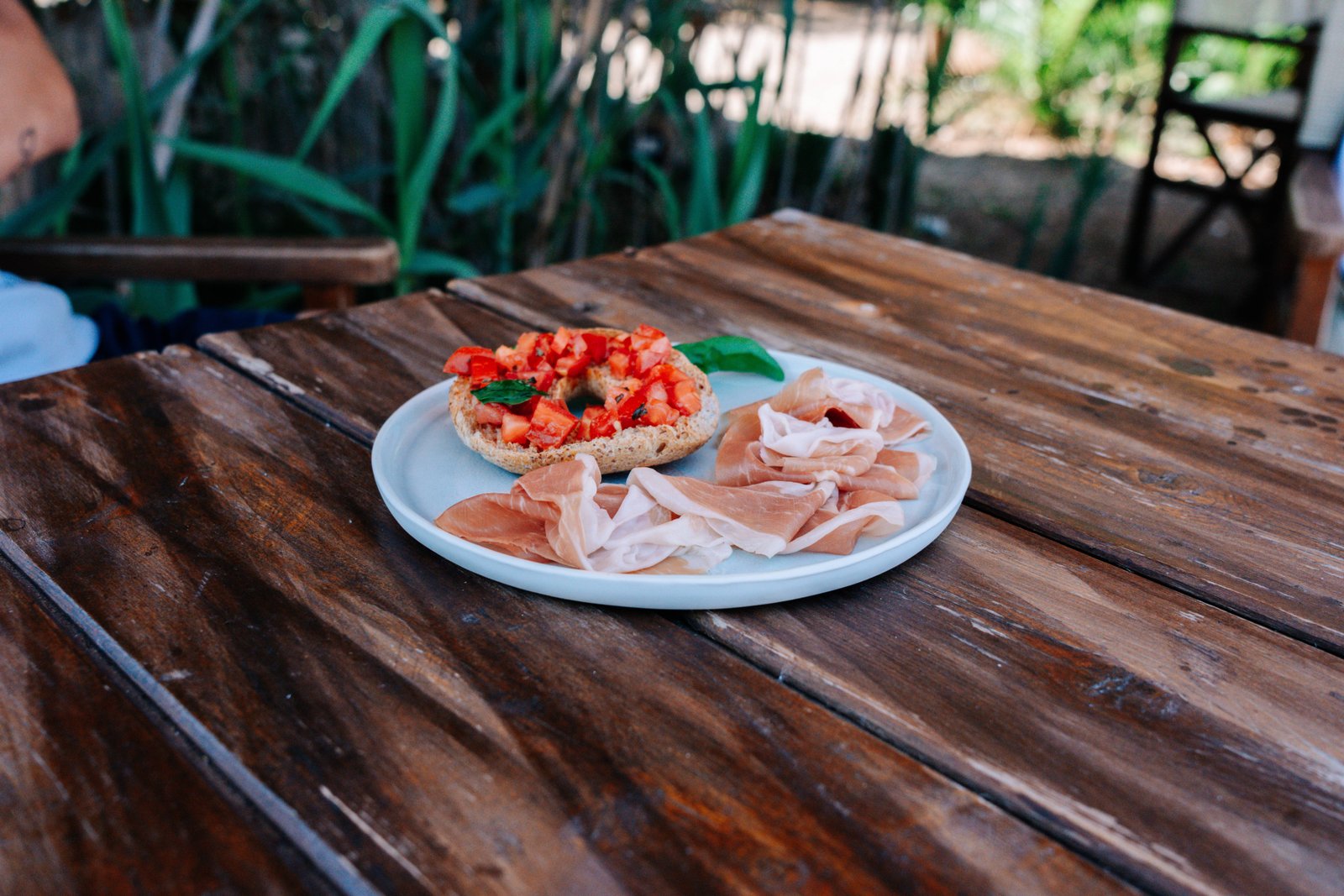 Piatto di Prosciutto di San Daniele DOP con bruschetta su un tavolo di legno all'aperto, pasto estivo leggero e conviviale