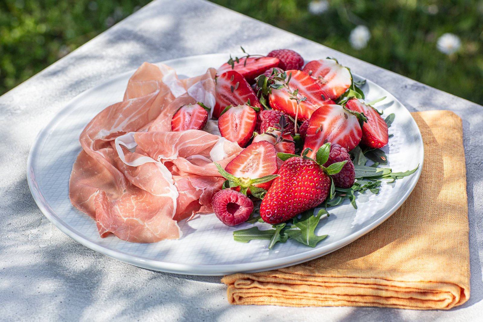 Piatto di Prosciutto di San Daniele DOP con fragole, lamponi e rucola, abbinamento proteico ideale per il recupero muscolare