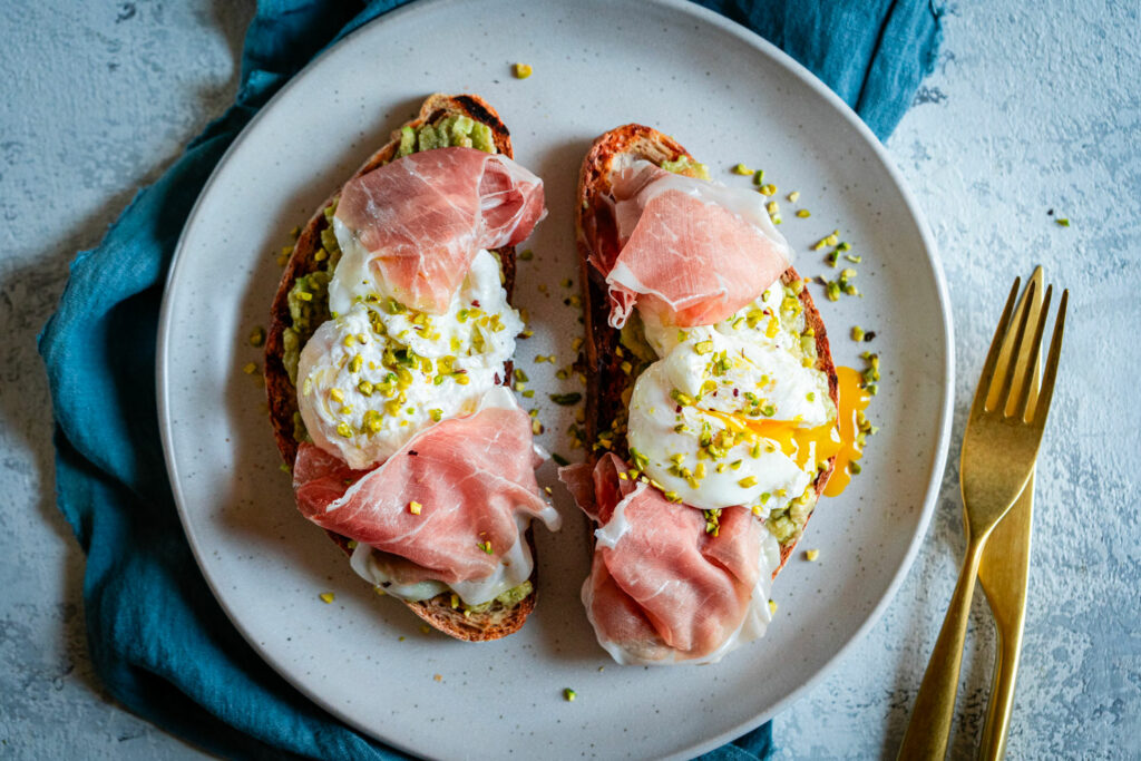 Avocado toast con uovo in camicia e roselline di Prosciutto di San Daniele DOP e granella di pistacchio