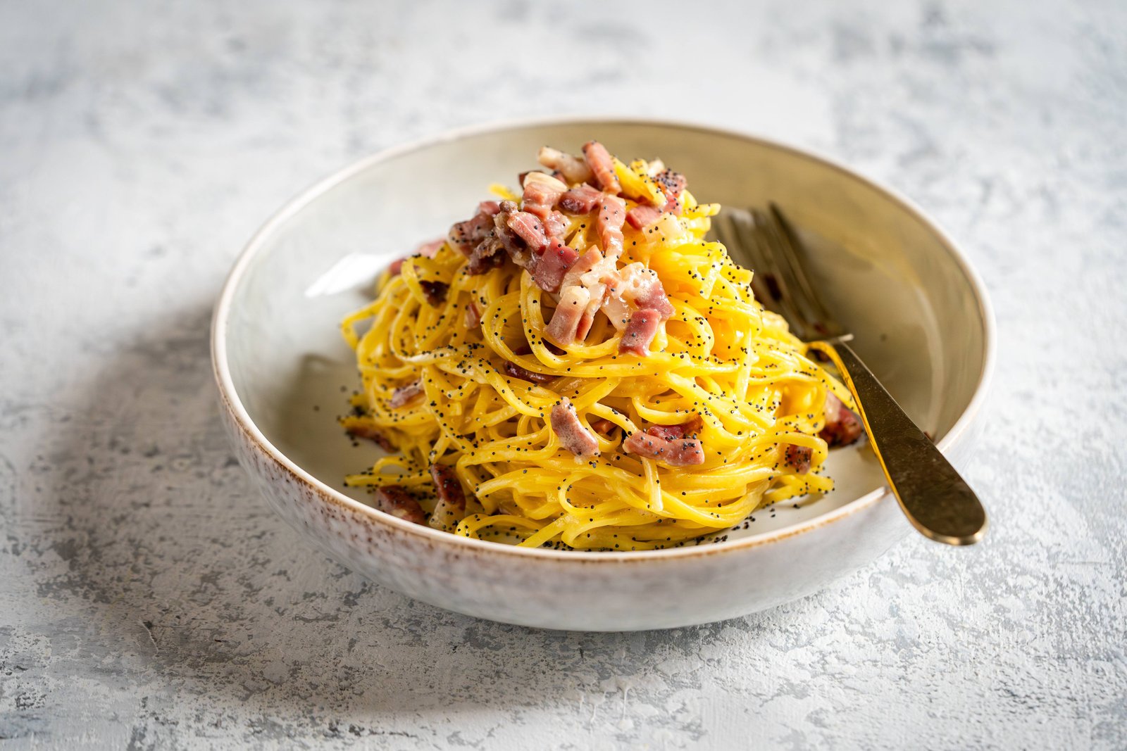 Piatto di tagliolini con Prosciutto di San Daniele DOP a dadini e semi di papavero, ricetta antispreco