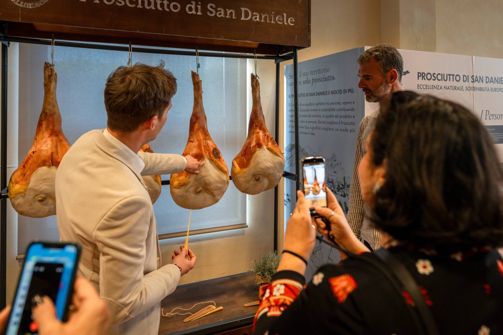 Masterclass per i consumatori: un relatore illustra le cosce di Prosciutto di San Daniele appese